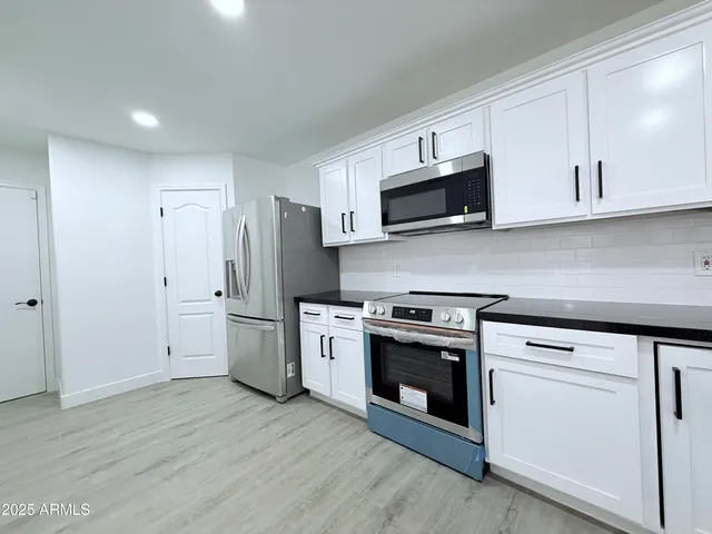 a kitchen with stainless steel appliances white cabinets and a stove top oven