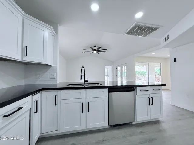 a kitchen with granite countertop white cabinets white appliances and a sink