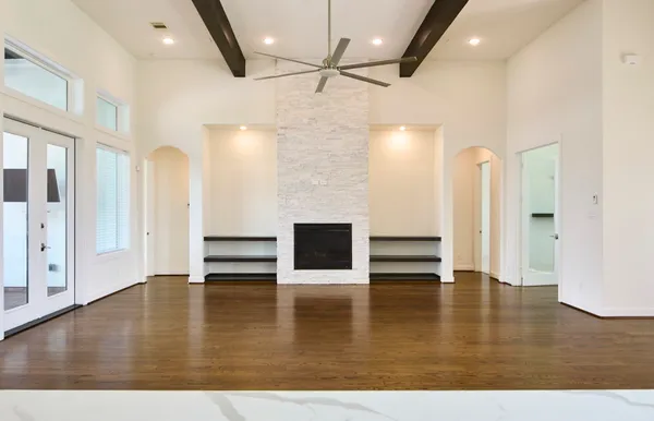 an empty room with wooden floor fireplace and staircase