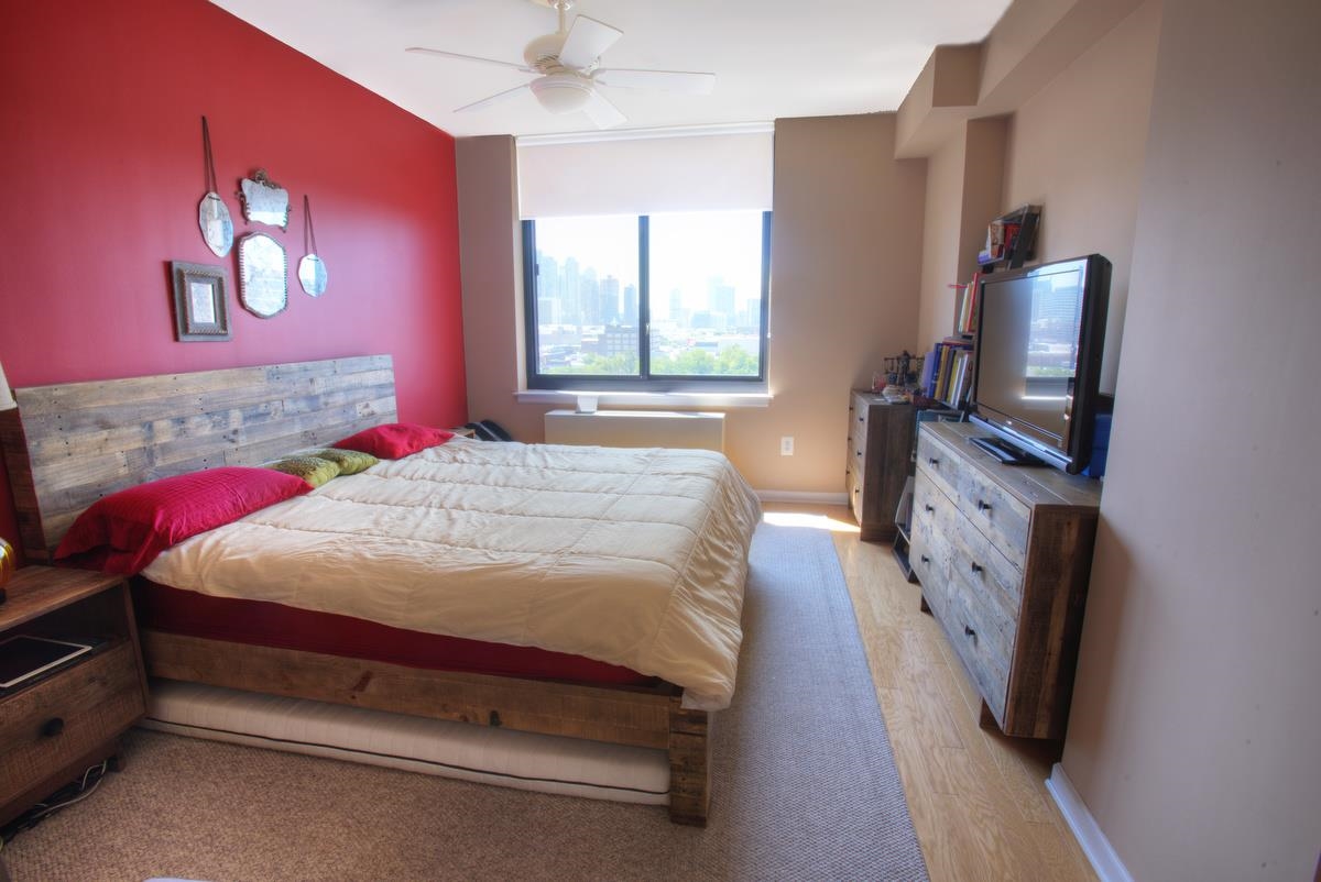 700 Grove Street, Unit 12J Jersey City, NJ 07310 - Photo 10 of 16 a bedroom with a bed flat screen tv and a window