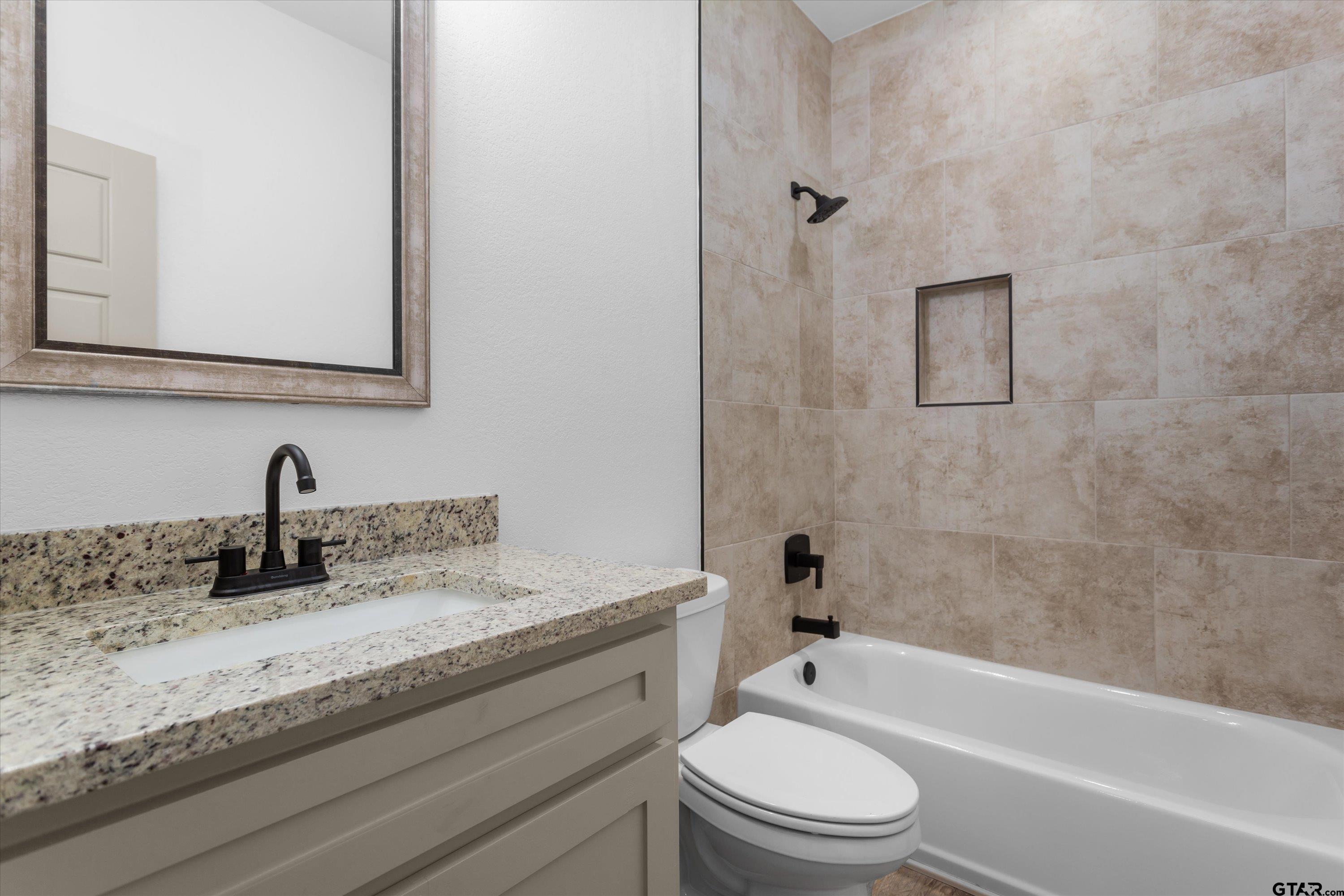 927 Nell Avenue Tyler, TX 75701 - Photo 17 of 20 a bathroom with a granite countertop toilet a sink and bathtub