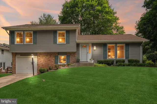 a brick house next to a yard with a large tree