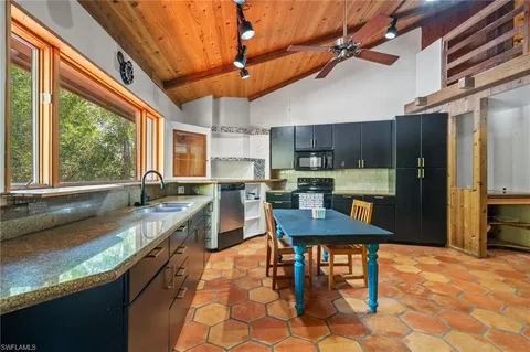 a kitchen with stainless steel appliances granite countertop a sink a stove a refrigerator cabinets dining table and chairs