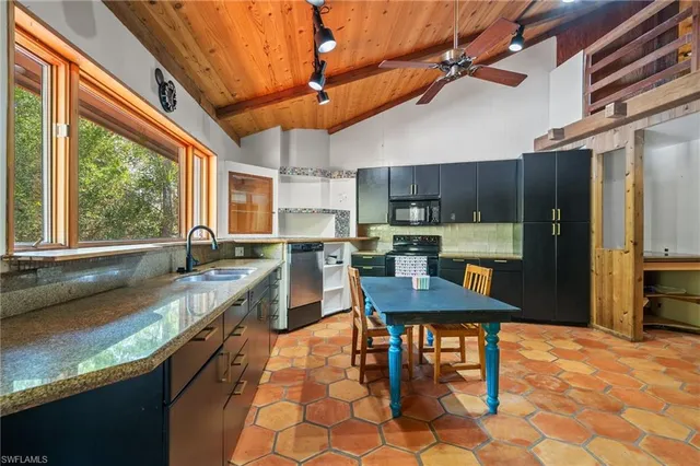 a kitchen with stainless steel appliances granite countertop a sink a stove a refrigerator cabinets dining table and chairs