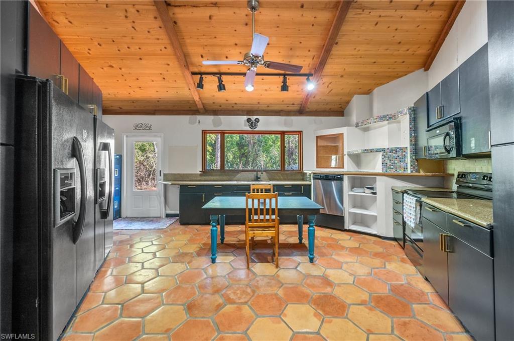 3775 27th Avenue Southwest Naples, FL 34117 - Photo 2 of 38 a kitchen with stainless steel appliances granite countertop a stove a sink dishwasher and a refrigerator with wooden cabinets