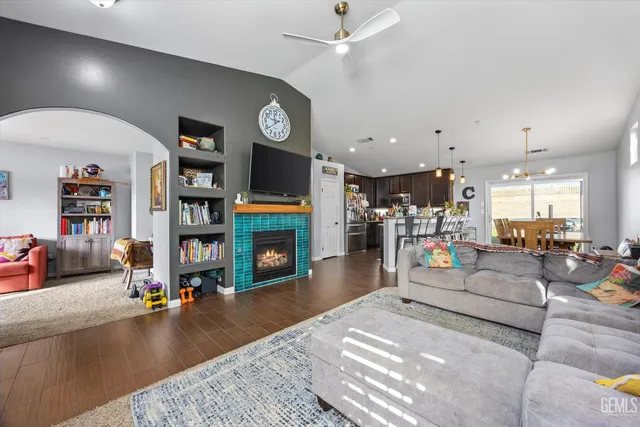 a kitchen with stainless steel appliances kitchen island granite countertop a refrigerator a stove a dining table and chairs with wooden floor