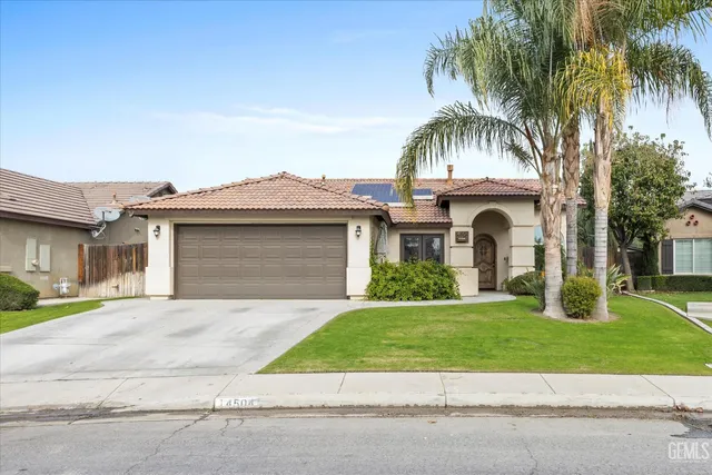 a front view of a house with a garden and palm trees
