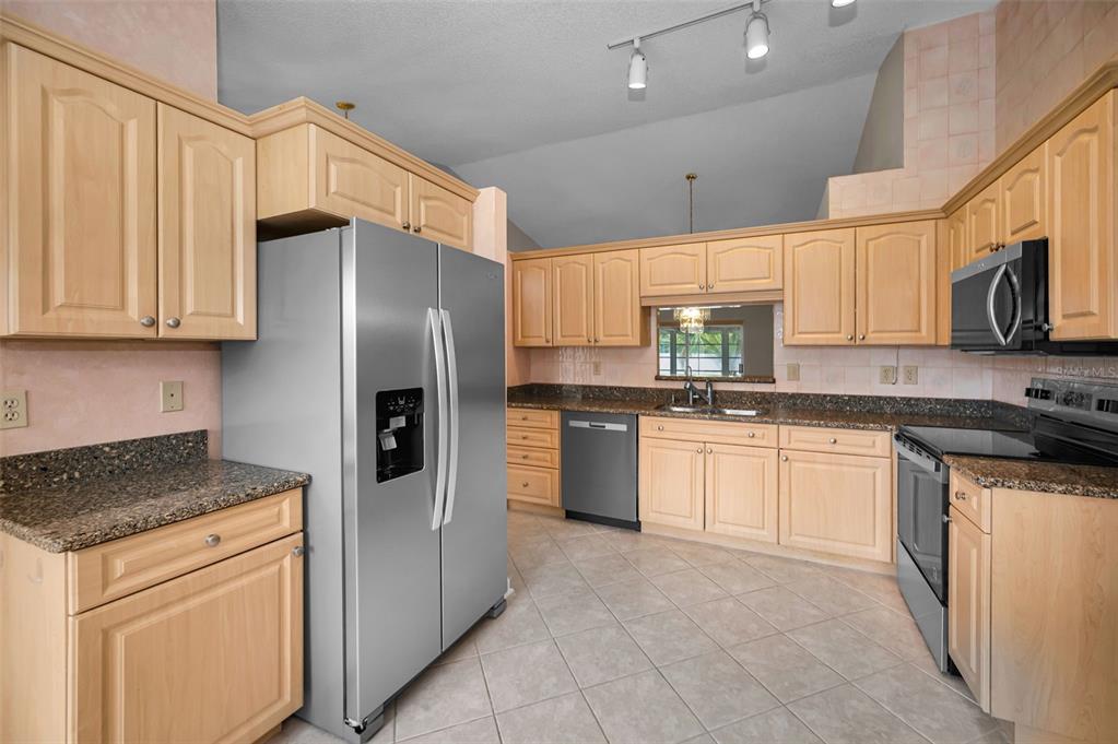 1481 Cairn Court Palm Harbor, FL 34683 - Photo 18 of 40 a kitchen with stainless steel appliances granite countertop a refrigerator sink and cabinets