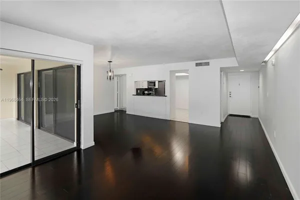 an empty room with wooden floor and a kitchen