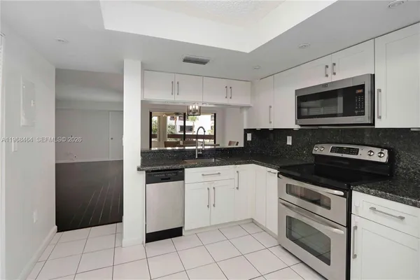 a kitchen with granite countertop white cabinets and stainless steel appliances