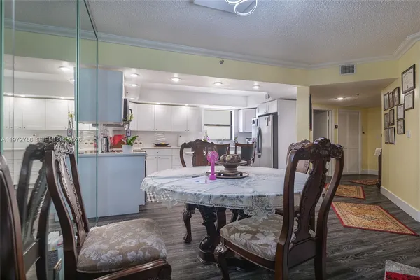 a dining room with stainless steel appliances furniture a rug and a kitchen view