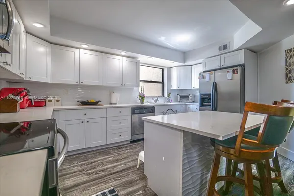 a kitchen with a table chairs refrigerator and microwave