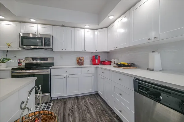 a kitchen with stainless steel appliances granite countertop a sink dishwasher a stove and white cabinets