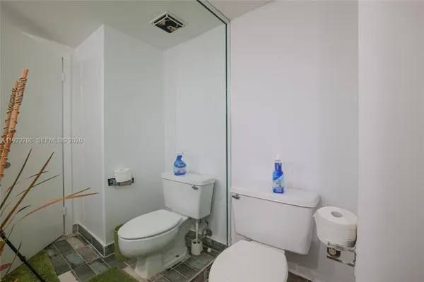 a white toilet sitting next to a white sink and vanity