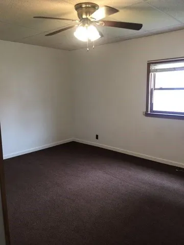 a bathroom with a toilet a sink a mirror and a window