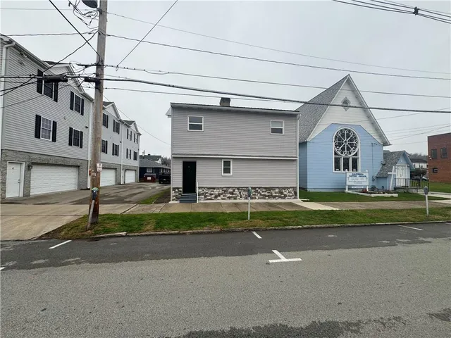 a front view of a house with a garden and parking