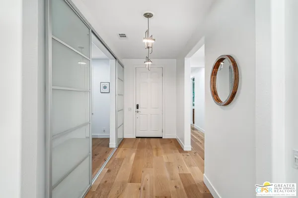 a view of a hallway with wooden floor and a chandelier