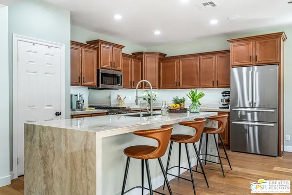 a kitchen with stainless steel appliances granite countertop a stove a refrigerator a sink a dining table and chairs