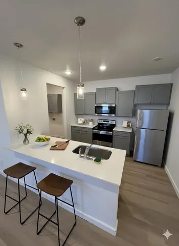 a kitchen with kitchen island a counter space a sink appliances and cabinets