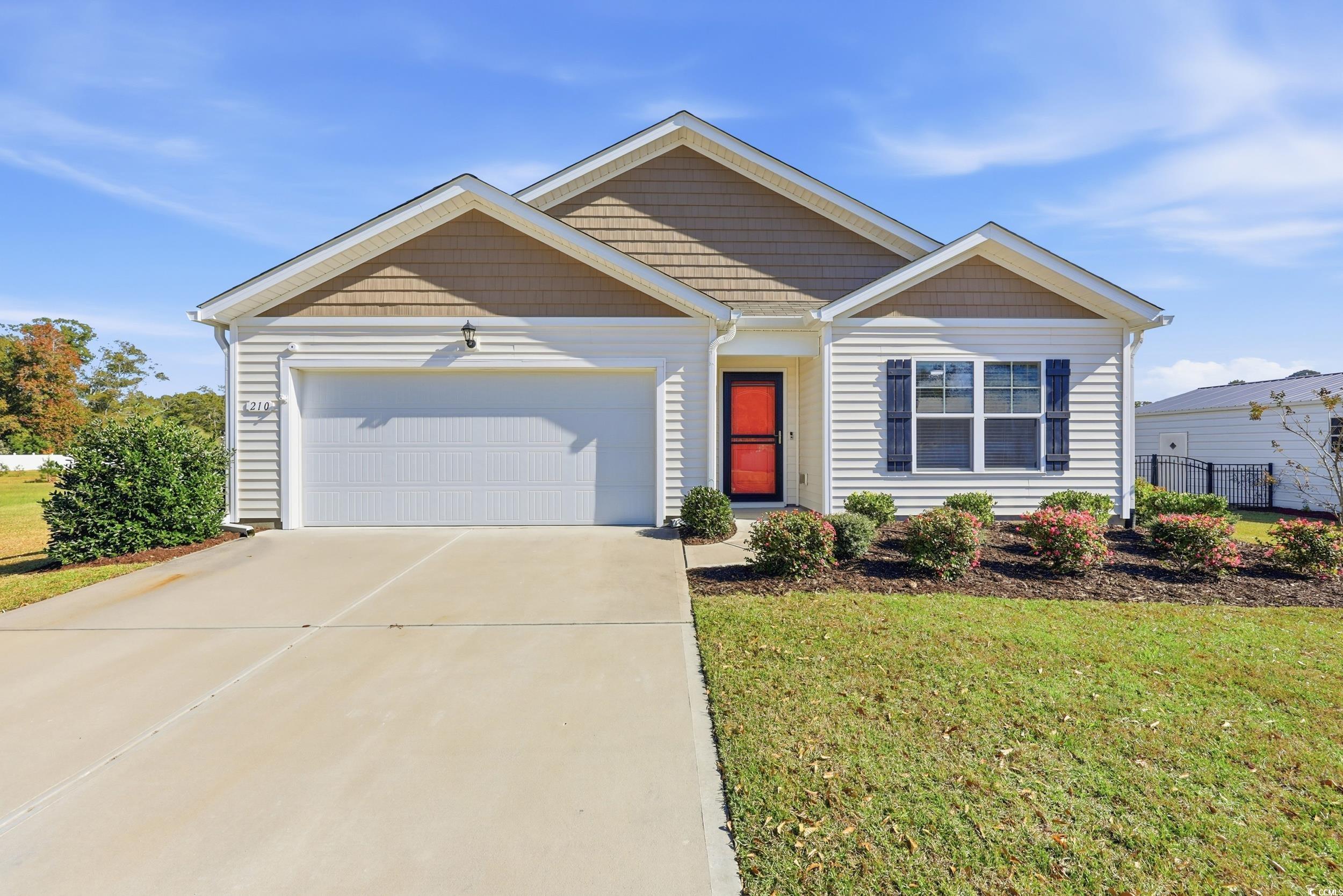 View of front of property featuring a front yard, driveway, and a garage