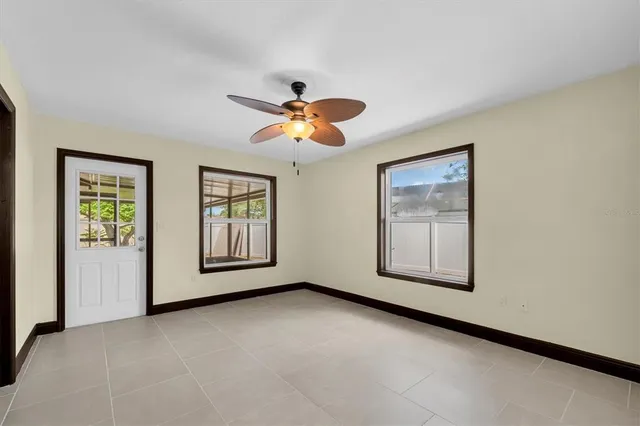 an empty room with windows and chandelier fan