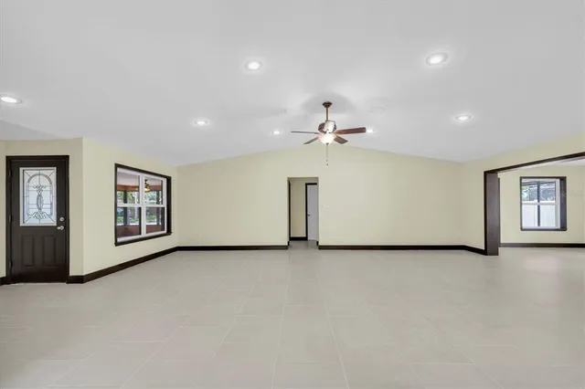 an empty room with windows and ceiling fan