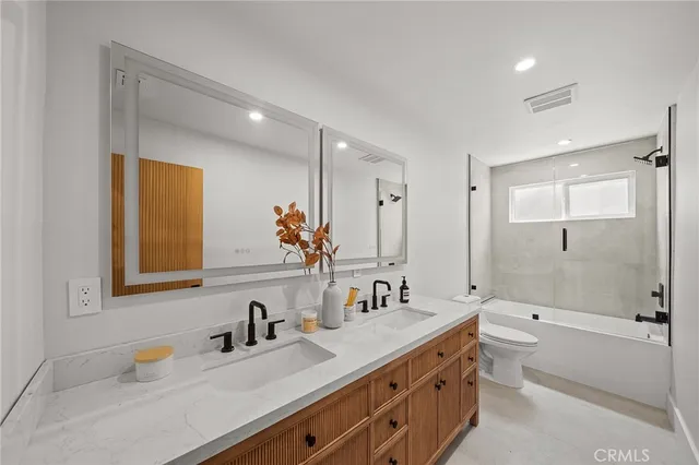 a bathroom with a double vanity sink toilet mirror and bathtub