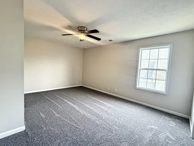 an empty room with windows and fan