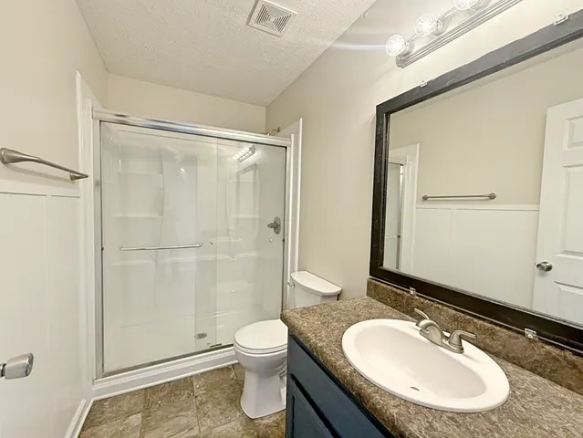 a bathroom with a granite countertop sink toilet a mirror and shower