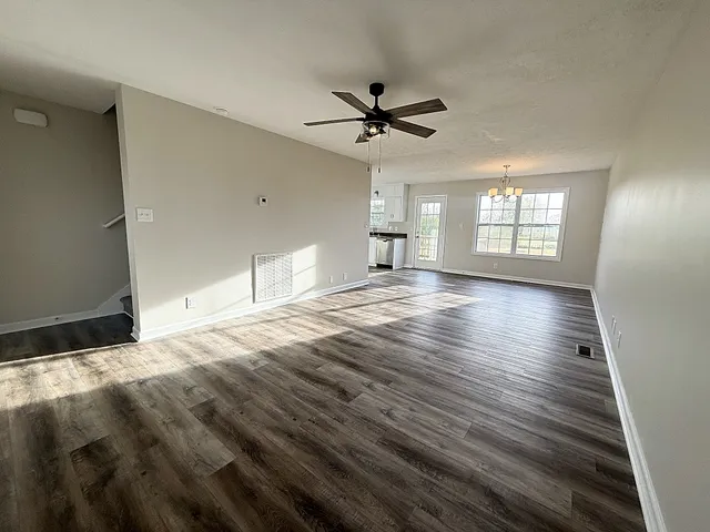 a view of an empty room with window and wooden floor