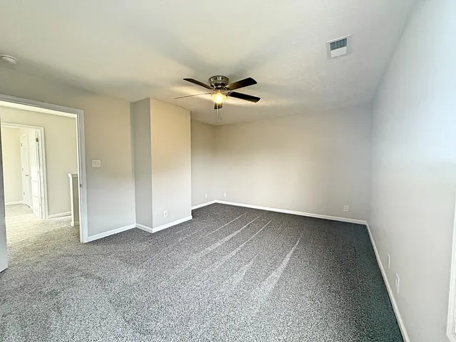 an empty room with a ceiling fan and a wooden floor