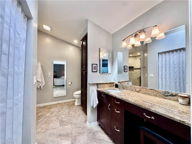 a spacious bathroom with a granite countertop sink a mirror and a shower