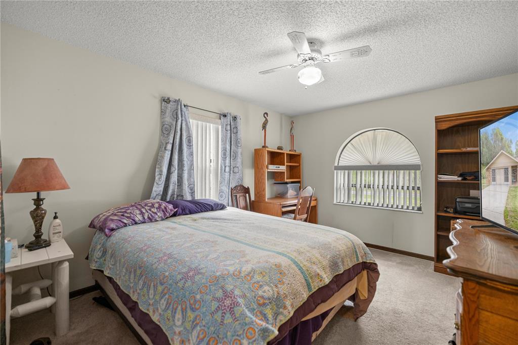 761 South Jeanne Avenue Inverness, FL 34453 - Photo 16 of 33 a bedroom with a bed a chandelier and a book shelf