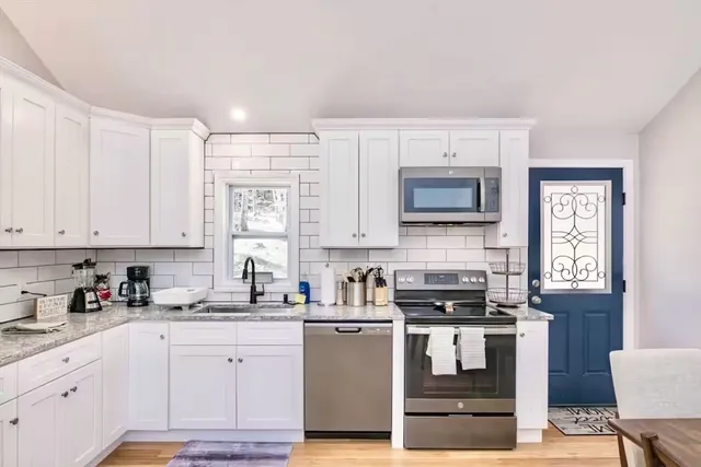 a kitchen with granite countertop white cabinets and white appliances