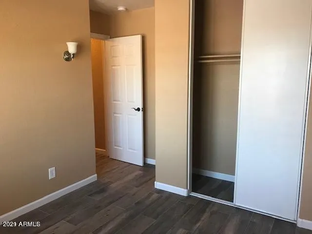a view of an empty room with wooden floor and closet