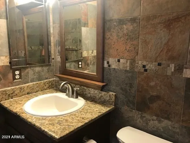 a bathroom with a granite countertop sink a toilet and shower