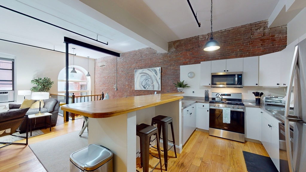 a kitchen with stainless steel appliances granite countertop a stove top oven a sink dishwasher a dining table and chairs with wooden floor