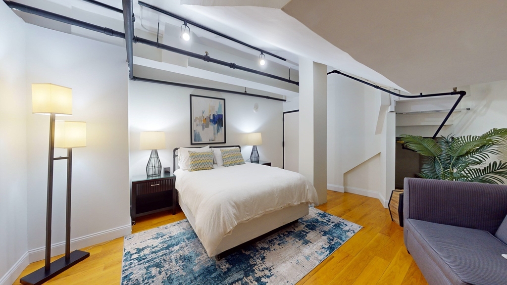 19 Stanhope Street, Unit 1D Boston, MA 02116 - Photo 18 of 30 a bedroom with a bed lamps and wooden floor