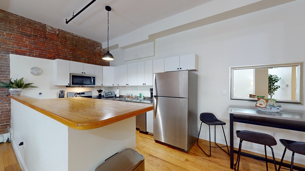 19 Stanhope Street, Unit 1D Boston, MA 02116 - Photo 6 of 30 a kitchen with stainless steel appliances granite countertop a refrigerator a stove a sink a dining table and chairs with wooden floor
