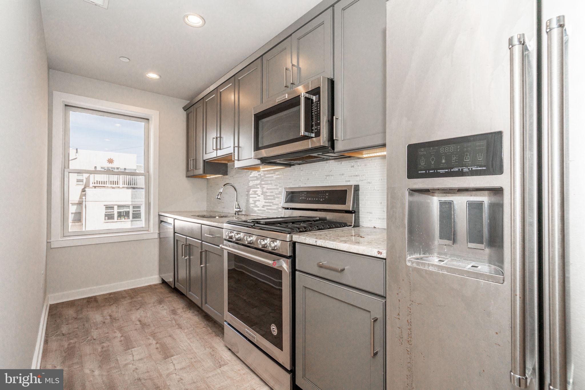 2609 Federal Street, Unit D Philadelphia, PA 19146 - Photo 2 of 27 a kitchen with stainless steel appliances granite countertop a stove a sink and a microwave