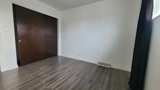an empty room with wooden floor and closet