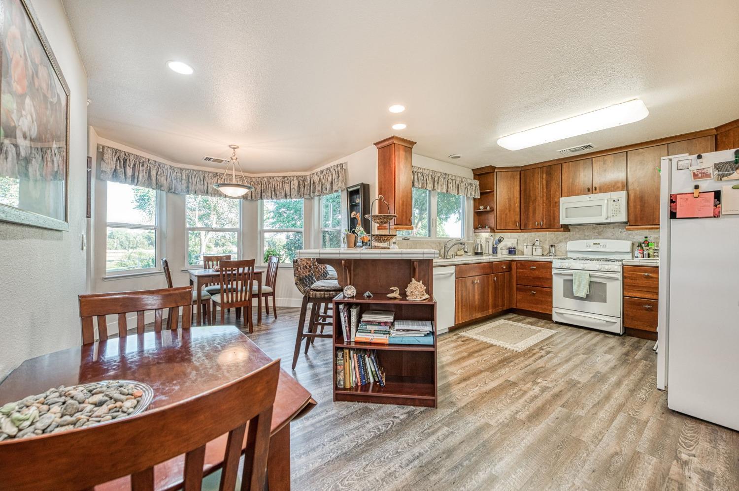 1098 South Rainbow Route Sanger, CA 93657 - Photo 57 of 70 a open kitchen with stainless steel appliances granite countertop a stove top oven a dining table and chairs with wooden floor
