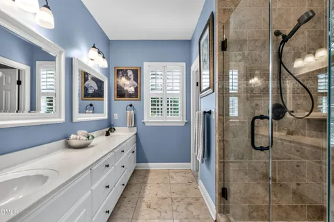 a bathroom with a granite countertop double vanity sink a mirror and shower