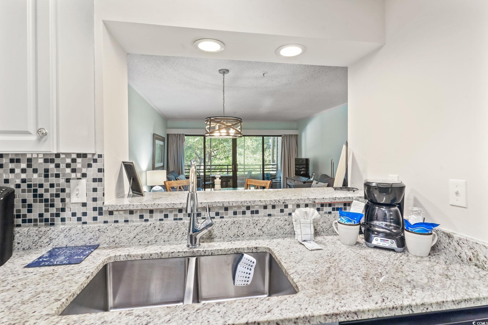 415 Ocean Creek Drive, Unit 2343 Myrtle Beach, SC 29572 - Photo 11 of 36 Kitchen featuring light stone countertops, a textured ceiling, backsplash, a chandelier, and decorative light fixtures