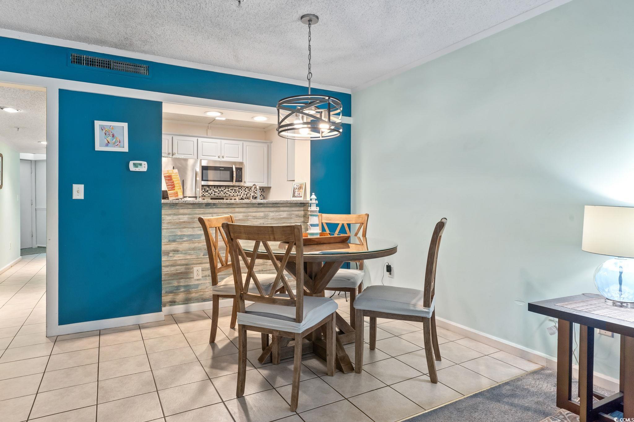 415 Ocean Creek Drive, Unit 2343 Myrtle Beach, SC 29572 - Photo 18 of 36 Dining area with a textured ceiling, light tile patterned flooring, and a chandelier