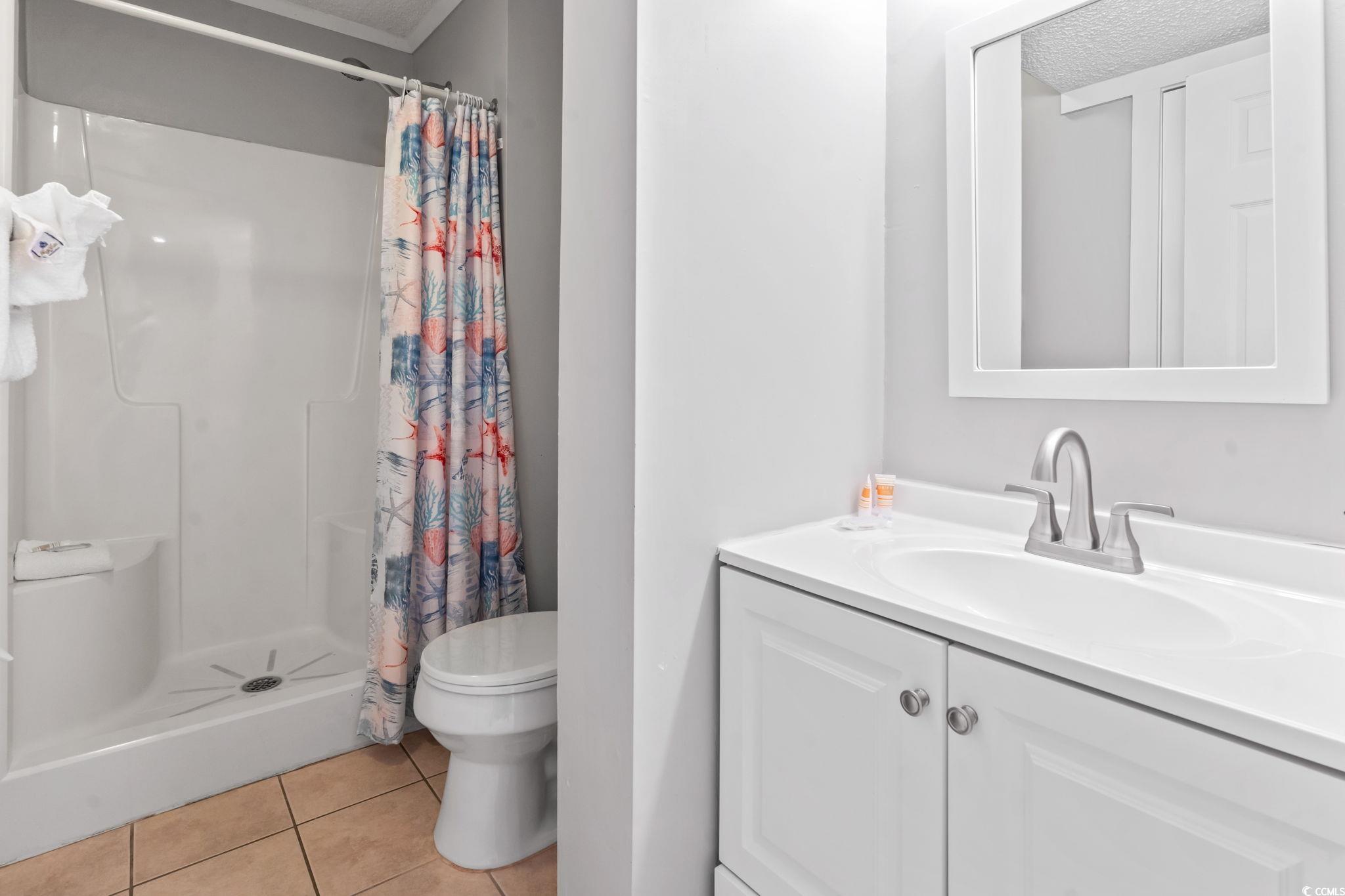 415 Ocean Creek Drive, Unit 2343 Myrtle Beach, SC 29572 - Photo 4 of 36 Full bath with light tile patterned floors, a stall shower, and vanity
