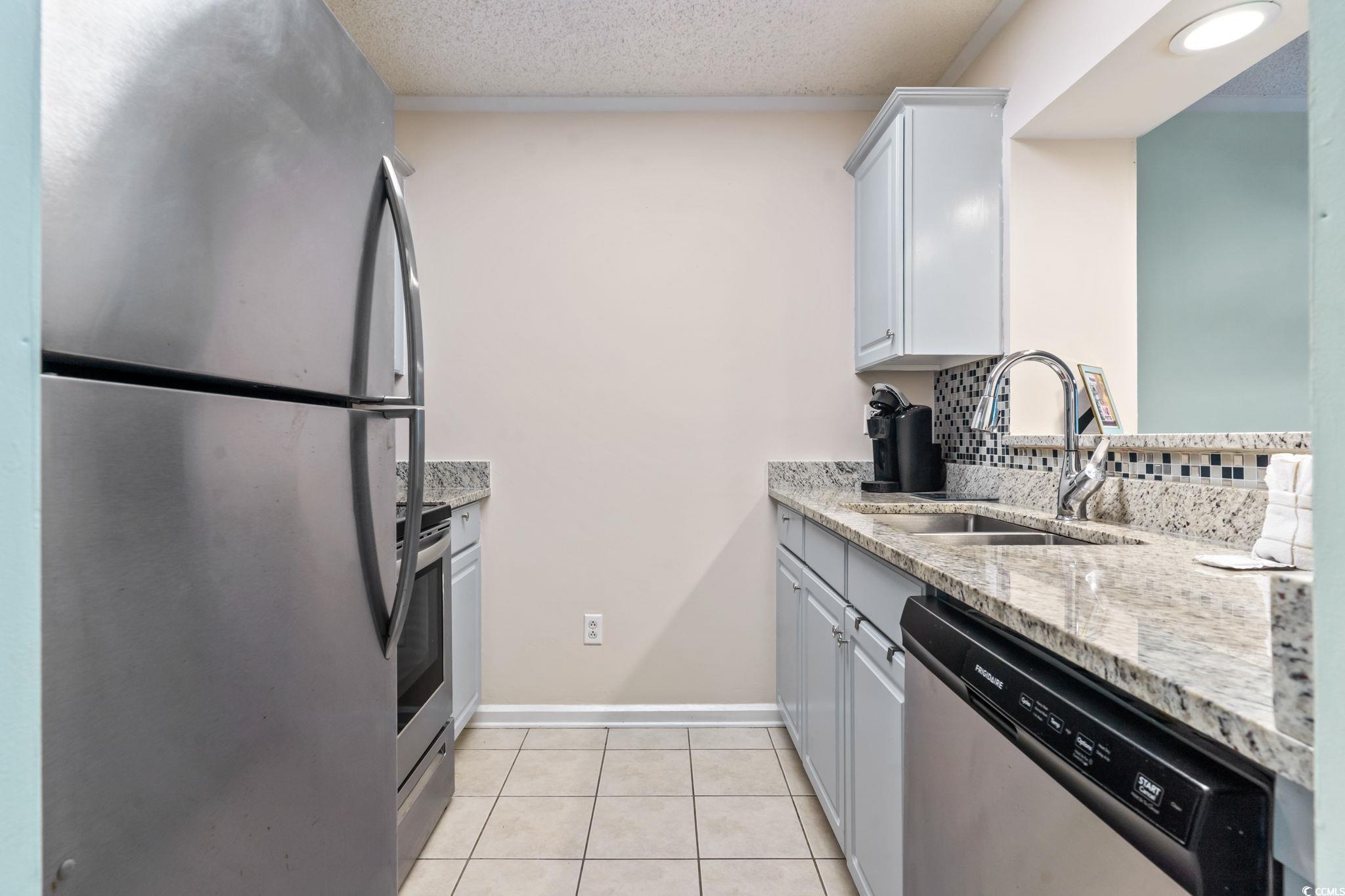 415 Ocean Creek Drive, Unit 2343 Myrtle Beach, SC 29572 - Photo 10 of 36 Kitchen featuring gray cabinets, appliances with stainless steel finishes, light stone counters, light tile patterned floors, and a textured ceiling