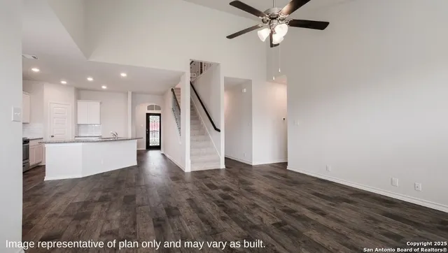 a view of an empty room with wooden floor and a ceiling fan