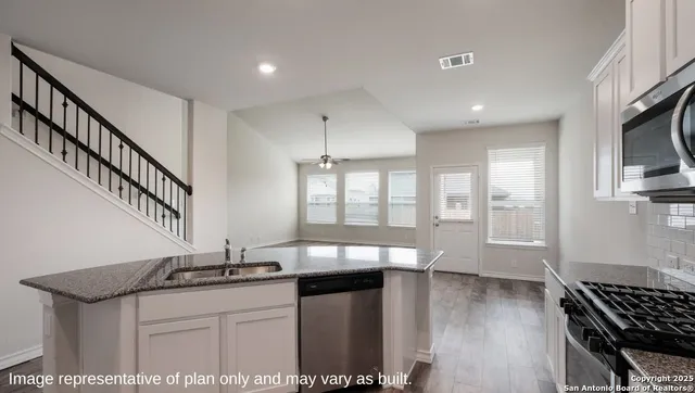 a kitchen with granite countertop a stove a sink and a refrigerator