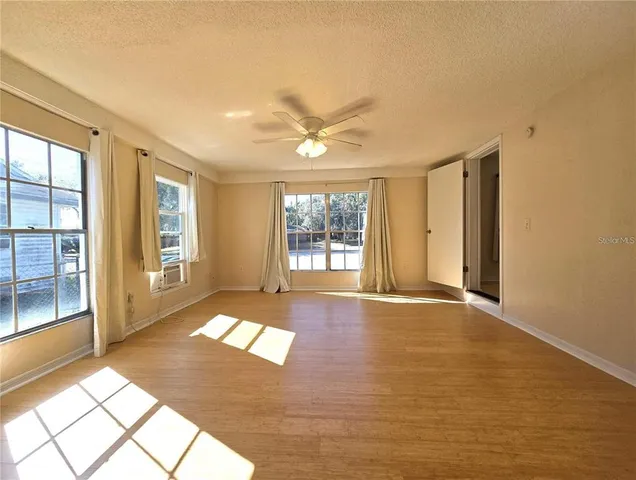 a view of an empty room with a window and wooden floor